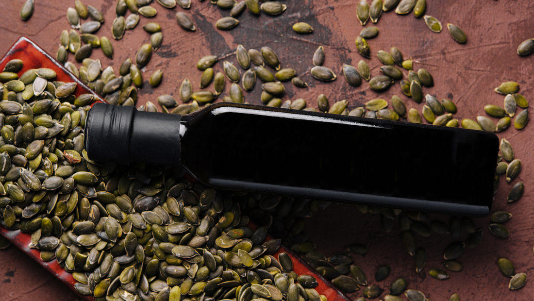 A dark glass bottle of pumpkin seed oil with Styrian pumpkin seeds on a table