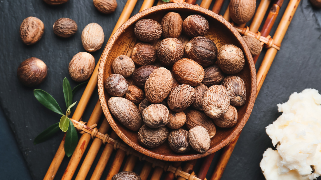 Shea nuts in a bowl on a wood object. Shea nuts and shea butter are on the table
